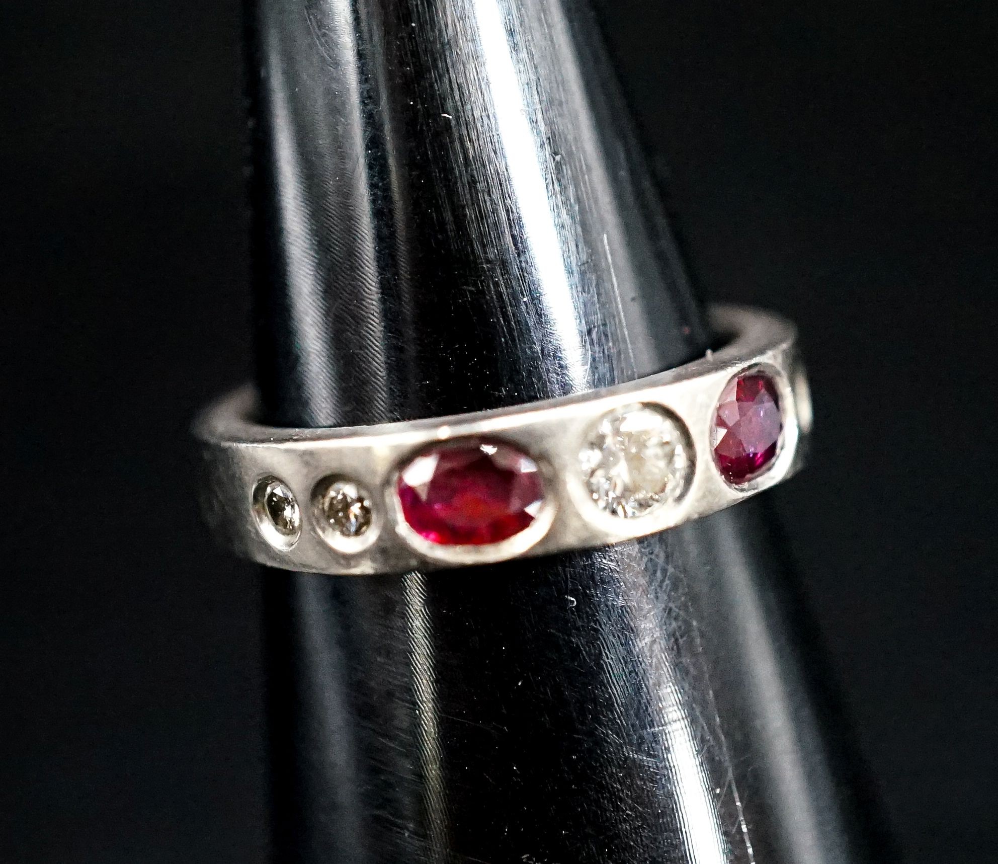 A white metal and gypsy set ruby and diamond set half hoop ring, size M, gross 6.1 grams.